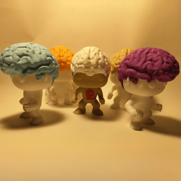 El simpático muñeco Brainvis sentado, sonriendo, con sus característicos lóbulos cerebrales de colores formando su cabello, junto al logotipo de la marca YOAM.