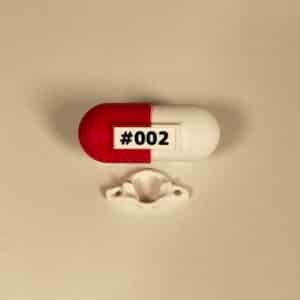 Fotografía de producto creativa con la píldora anatómica y la vértebra C1 blanca, ideal para merchandising de salud.